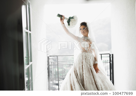 Portrait of stunning bride with long hair posing with great bouquet 100477699