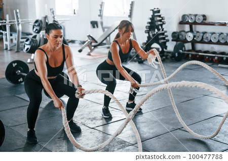 Young people with sportive body shapes doing crossfit by using knots Young people with sportive body shapes doing crossfit by using knots 100477788