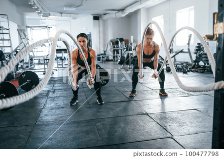 Young people with sportive body shapes doing crossfit by using knots 100477798