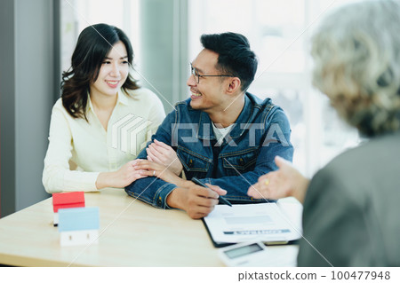 Guarantee Insurance Sign a contract, couple a smiling couple is signing a contract to invest in real estate with the Mortgage officer with the bank. Guarantee Insurance Sign a contract, couple a smiling couple is signing a contract to invest in real estate with the Mortgage officer with the bank. 100477948