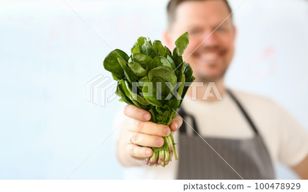 Smiling cook is holding lettuce or sorrel leaves closeup 100478929