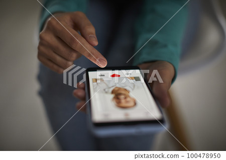 African american woman's hands giving like to a man's photo on her mobile dating application. 100478950