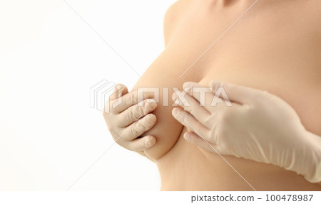 Women hands in rubber gloves cover naked breasts 100478987