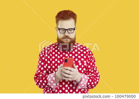 Serious funny bearded fat young guy making call or text messaging on mobile phone 100479000