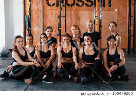 Sitting on floor. Group of young sportive people have crossfit day indoors in gym Sitting on floor. Group of young sportive people have crossfit day indoors in gym 100479200