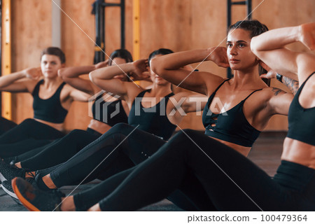 Busy by doing exercises. Group of young sportive people have crossfit day indoors in gym 100479364