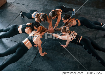 Plank exercise. Group of young sportive people have crossfit day indoors in gym Plank exercise. Group of young sportive people have crossfit day indoors in gym 100479552
