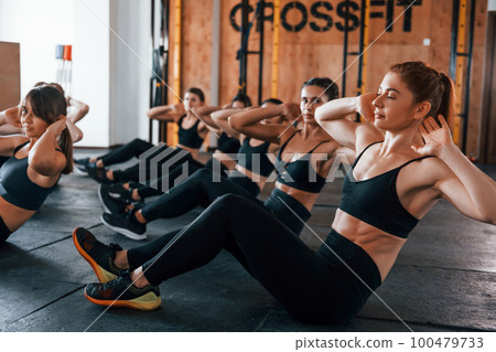 Doing abs. Group of young sportive people have crossfit day indoors in gym Doing abs. Group of young sportive people have crossfit day indoors in gym 100479733