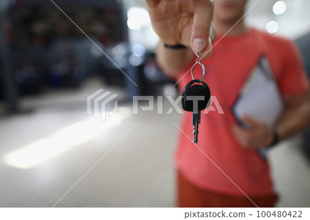 Person mechanic handing over key to car in workshop Person mechanic handing over key to car in workshop 100480422