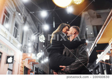 Embracing each other. Happy multiracial couple together outdoors in the city celebrating New year Embracing each other. Happy multiracial couple together outdoors in the city celebrating New year 100480630