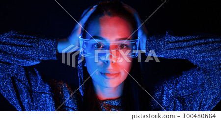 Portrait of young girl that is in eyeglasses in blue neon lighting 100480684