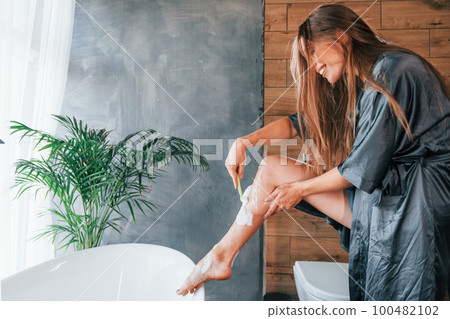 Beautiful young woman have free time at home in the bath. Shaves legs Beautiful young woman have free time at home in the bath. Shaves legs 100482102