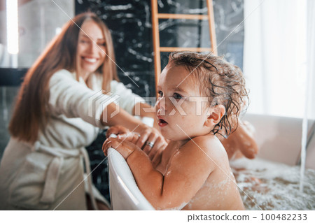 Young mother helps her son and daughter. Two kids washing in the bath Young mother helps her son and daughter. Two kids washing in the bath 100482233