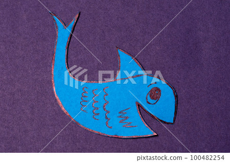 Blue april fool fish cut out of colored paper on a purple background Blue april fool fish cut out of colored paper on a purple background 100482254