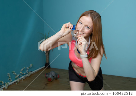 Woman in sportswear rejoices at a won sports medal Woman in sportswear rejoices at a won sports medal 100482512