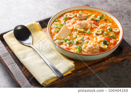 Asopao de pollo is a Caribbean dish that consists of sofrito, rice, tomato paste, and bite sized pieces of chicken closeup on the bowl. Horizontal 100484168