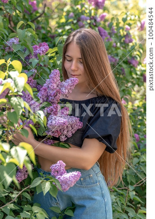 portrait of young woman with long hair outdoors in blooming lilac garden portrait of young woman with long hair outdoors in blooming lilac garden 100484544
