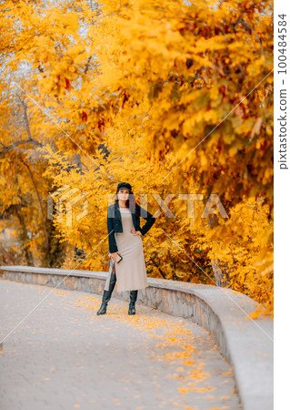 A woman walks outdoors in autumn, enjoys the autumn weather. 100484584
