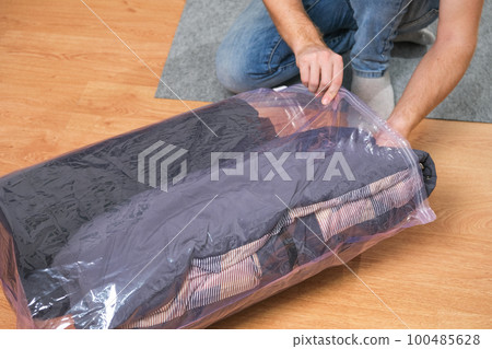 A man folds winter jackets and puts them in a 100485628