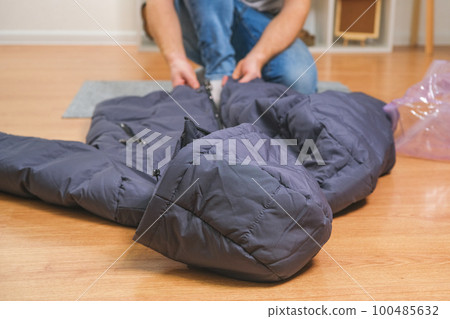 A man folds winter jackets and puts them in a 100485632