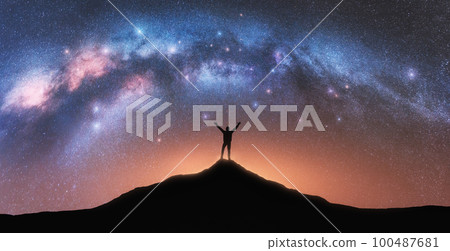 Milky Way and happy man with backpack on mountain peak at night 100487681