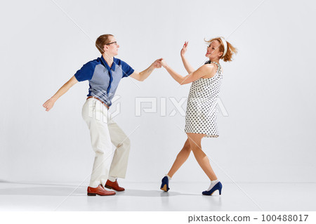 Young excited man and woman wearing stylish clothes dancing retro dance isolated on white background 100488017