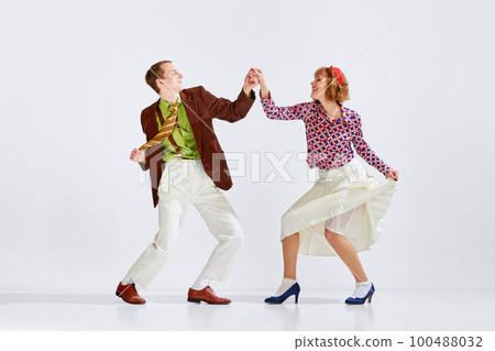 Showing positive energy. Young man and woman in stylish clothes dancing retro dance against grey studio background Showing positive energy. Young man and woman in stylish clothes dancing retro dance against grey studio background 100488032
