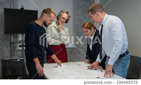 Four business people review and discuss blueprints. Designers engineers at a meeting. Four business people review and discuss blueprints. Designers engineers at a meeting. 100488378