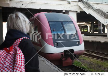 Blonde woman with backpack sstanding on railway station and looking on train Blonde woman with backpack sstanding on railway station and looking on train 100489305