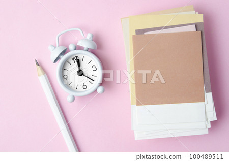 The Heap of blank paper note for your text and alarm clock on pink color background. The Heap of blank paper note for your text and alarm clock on pink color background. 100489511