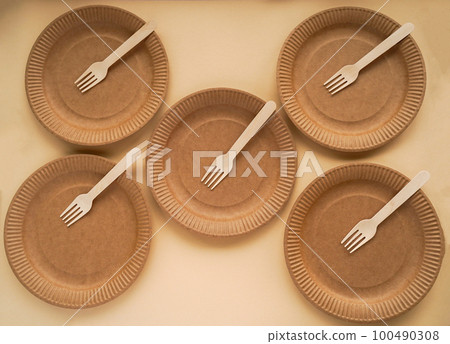 Five craft disposable plates with wooden forks on beige background. Top view. Biodegradable concept and conservation of natural resources 100490308