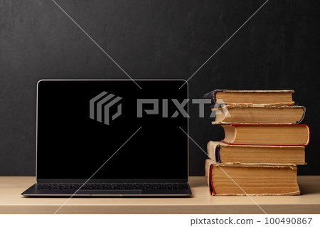 Laptop and stack of books 100490867