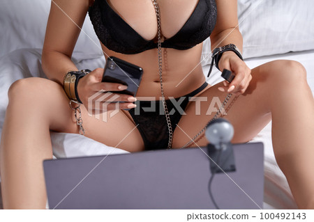 Beautiful, young girl posing in front of a web camera, working as a model. He takes off his bra. The concept of online flirting, sex on the Internet. Beautiful, young girl posing in front of a web camera, working as a model. He takes off his bra. The concept of online flirting, sex on the Internet. 100492143