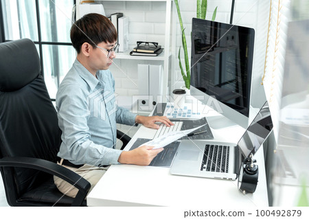 Male programmer is programing to developing program app and website of corporate while working to checking program code and debugging on multiple screen at modern software office Male programmer is programing to developing program app and website of corporate while working to checking program code and debugging on multiple screen at modern software office 100492879