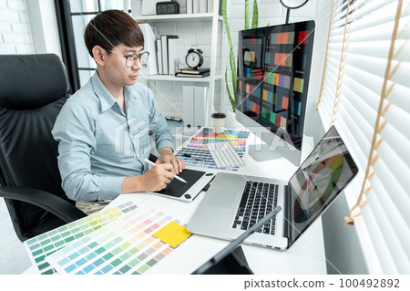 Male graphic designer is choosing color swatch samples on multiple screens and sketching on tablet Male graphic designer is choosing color swatch samples on multiple screens and sketching on tablet 100492892
