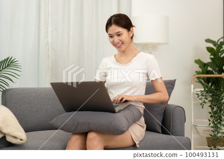 Teenage girl is using laptop to listening lecture of lecturer while sitting comfortable on the couch in living room to studying e-learning from study remotely at home Teenage girl is using laptop to listening lecture of lecturer while sitting comfortable on the couch in living room to studying e-learning from study remotely at home 100493131