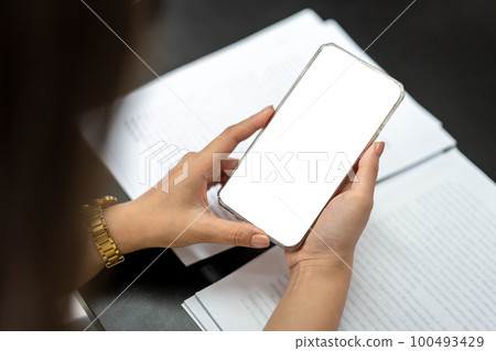 Business woman is showing white blank screen on smartphone while checking data and working about new project of business in modern office 100493429