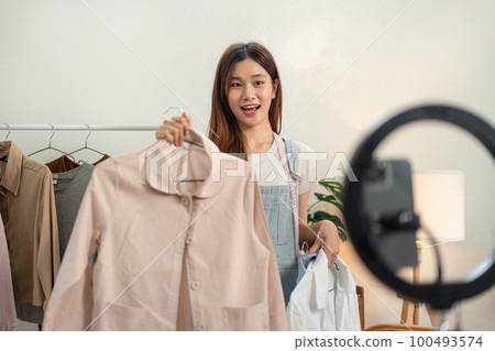 Female online seller is using smartphone to broadcast live on Vlog for introduce fashions while showing Female online seller is using smartphone to broadcast live on Vlog for introduce fashions while showing 100493574