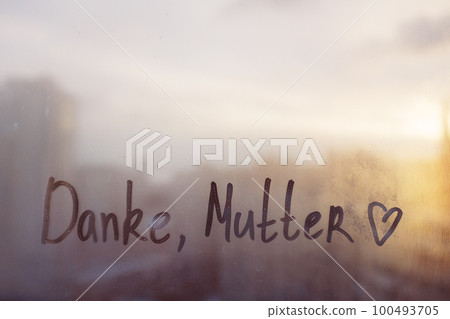 Handwritten lettering text Danke Mutter in german is Thanks mother in english written finger with heart shape on rainy window Handwritten lettering text Danke Mutter in german is Thanks mother in english written finger with heart shape on rainy window 100493705