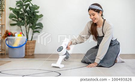 Housekeeper is using cordless vacuum cleaner with handheld for cleanups and vacuuming dirt on carpet Housekeeper is using cordless vacuum cleaner with handheld for cleanups and vacuuming dirt on carpet 100493826