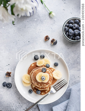 pancakes with fresh blueberries, banana on gray background 100493988