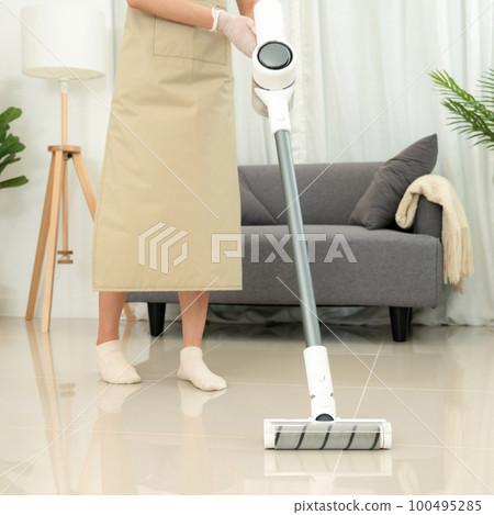 Housekeeper is use mop with vacuum cleaner to housekeeping with vacuuming and wiping dirty laminate 100495285