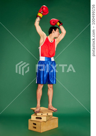 Portrait of boxer posing after win and kissing his biceps isolated over green background. Concept of victory, sport, competition, training, energy. Banner with copy space for ad, text Portrait of boxer posing after win and kissing his biceps isolated over green background. Concept of victory, sport, competition, training, energy. Banner with copy space for ad, text 100499156