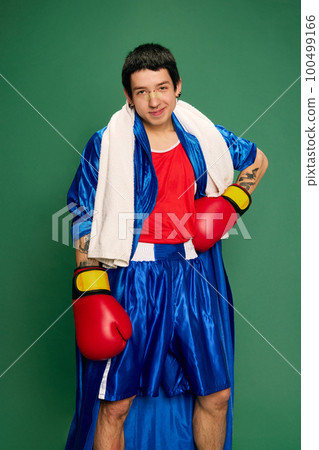 Funny portrait of beginner boxer in robe and shorts posing after fight isolated over green background. Sport, funny meme emotions, male hobbies Funny portrait of beginner boxer in robe and shorts posing after fight isolated over green background. Sport, funny meme emotions, male hobbies 100499166