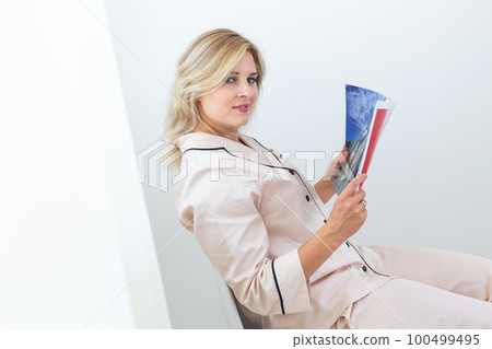 Woman wears pajama reads magazine in living room. Homewear, sleepwear, shopping and sale Woman wears pajama reads magazine in living room. Homewear, sleepwear, shopping and sale 100499495