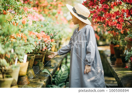Child planting spring flowers. Little girl gardener plants azalea. Child taking care of plants. Gardening tools and water can for kids Child planting spring flowers. Little girl gardener plants azalea. Child taking care of plants. Gardening tools and water can for kids 100500894