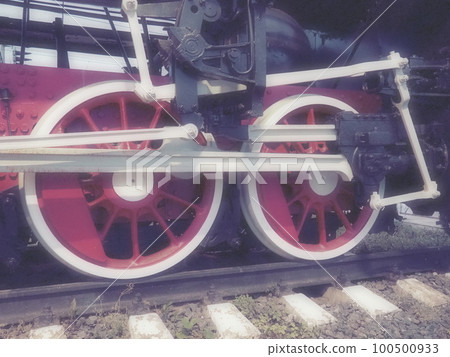 Retro vintage wheels of a locomotive or train close up. Red large heavy metal wheels with piston guiding mechanisms. Locomotive of the 19th - 20th centuries with a steam engine. Blurred soft focus 100500933
