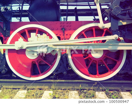 Retro vintage wheels of a locomotive or train close up. Red large heavy metal wheels with piston guiding mechanisms. Locomotive of the 19th - 20th centuries with a steam engine. Retro style 100500947