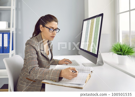 Business accountant checking financial records and working with spreadsheets on computer Business accountant checking financial records and working with spreadsheets on computer 100501535
