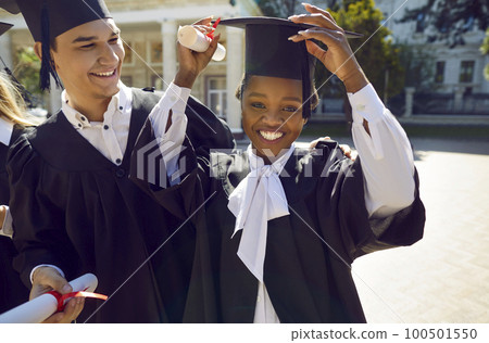 Portrait of happy African American girl in cap and gown having fun on graduation day 100501550